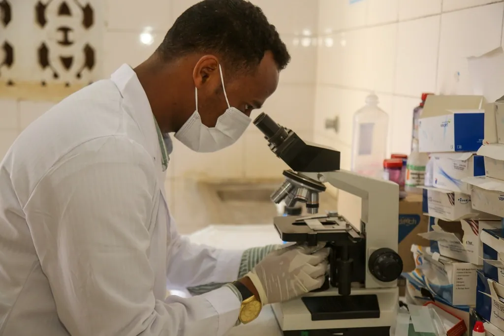 Analyst looking at a sample through a microscope