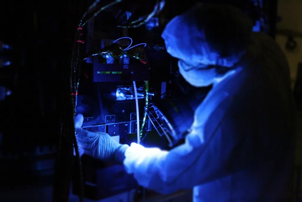 Technician adjusting automated equipment under ultraviolet light